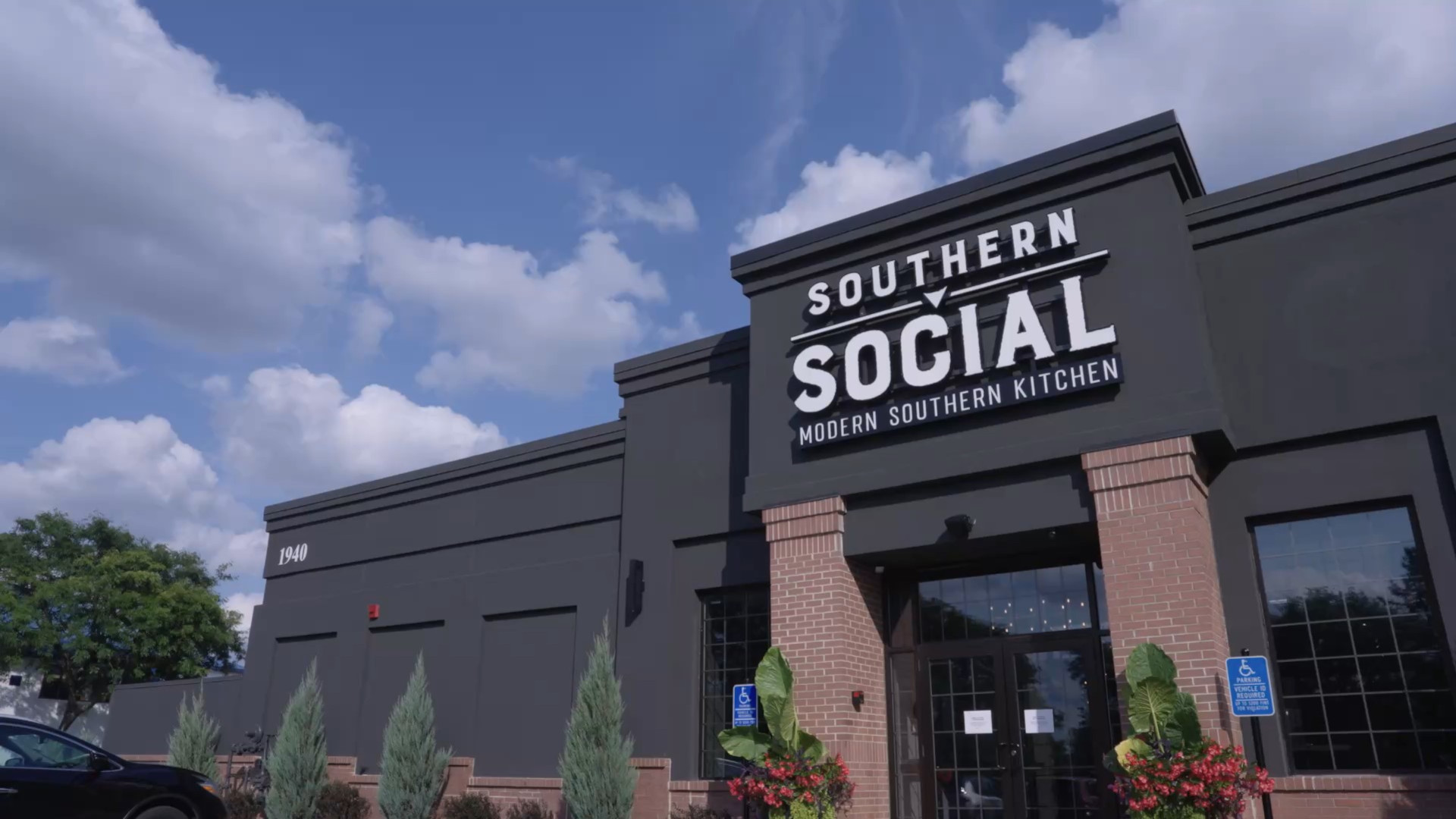 Exterior view of Southern Social, a modern black restaurant building with bold white signage reading “Southern Social – Modern Southern Kitchen” under a blue sky with clouds.